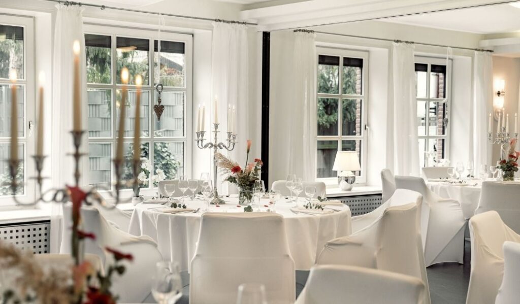 Raum mit festlich eingedeckten runden Tischen
